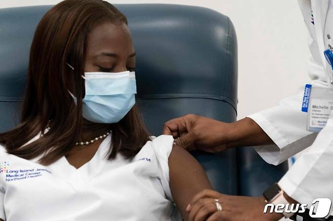 뉴욕 퀸스의 롱아일랜드 주이시 메디컬 센터에서 샌드라 린지 간호사가 미셸 체스터 의사로부터 화이자ㆍ바이오앤테크의 코로나19 백신을 미국서 처음으로 접종받고 있다.  사진제공=AFP=뉴스1
