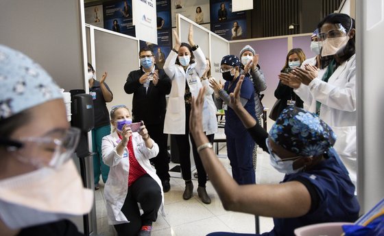 15일(현지시간) 미국 뉴욕시 마운트시나이병원 코로나19 백신접종센터에서 의료진이 화이자 백신을 맞은 간호조무사 재니스 메이어(오른쪽 맨 앞)에게 박수를 보내고 있다. [EPA=연합뉴스]