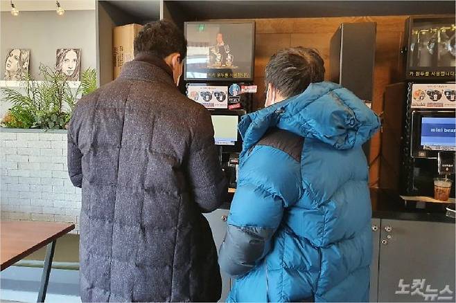 두 중년 남성이 강릉시 구정면의 한 무인 카페에서 기계를 작동해 직접 커피를 뽑고 있다. (사진=유선희 기자)