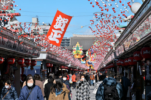일본 도쿄의 아사쿠사 인근 거리에 17일 연말과 새해를 기념하는 장식이 설치된 가운데 마스크를 쓴 시민들이 다니고 있다. 2020.12.18 UPI 연합뉴스