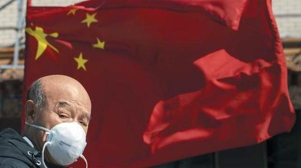 지난달 3일 중국 베이징에서 마스크를 쓴 한 남성이 국기인 오성홍기 앞을 지나가고 있다 /AP 연합뉴스
