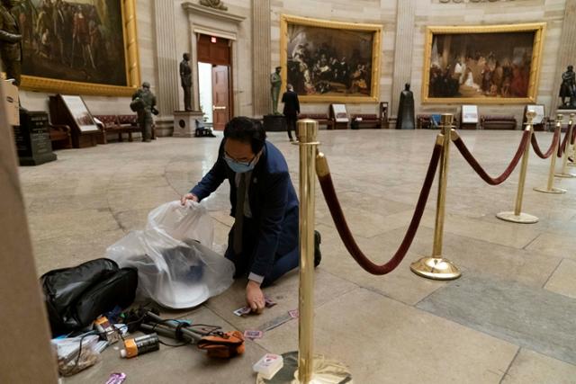 한국계 앤디 김 의원이 7일 미국 워싱턴 의회의사당에서 바닥에 무릎을 꿇은 채 쓰레기를 치우고 있다. 전날 트럼프 대통령 지지자들이 의사당에 난입해 사상 초유의 폭력 사태가 빚어졌다. 워싱턴=AP 연합뉴스