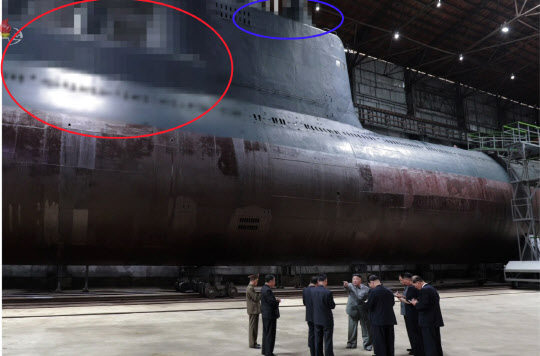 김정은 북한 노동당 위원장이 9일 핵추진 잠수함 개발이 이뤄지고 있음을 처음으로 공식화했다. 북한은 당초 잠수함발사탄도미사일(SLBM) 탑재가 가능한 3000t급 디젤 추진 잠수함을 건조해온 것으로 알려졌고 핵추진 잠수함 도입 의사를 공식화한 건 이번이 처음이다. 사진은 2019년 7월 북한 조선중앙TV가 김 위원장이 새로 건조한 잠수함을 시찰했다고 보도하면서 공개한 잠수함 모습. 당시 중앙TV는 시찰 장면이 담긴 사진을 공개하면서 잠수함에서 SLBM 발사관이 위치했을 것으로 추정되는 부분(붉은 원)과, 함교탑 위 레이더와 잠망경 등이 위치했을 것으로 추정되는 부분(파란 원)을 각각 모자이크 처리했다(사진=연합뉴스).