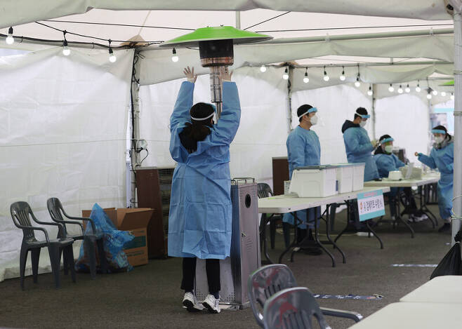 지난해 12월29일 오전 서울역광장에 마련된 코로나19 임시선별검사소에서 의료진이 손을 녹이고 있다. 연합뉴스