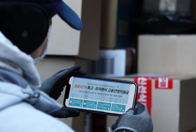 6일 서울 중구 충무로 인근 한 골목에서 한 택배 기사가 고용안정지원금 온라인 신청 사이트를 찾아보고 있다. 뉴스1