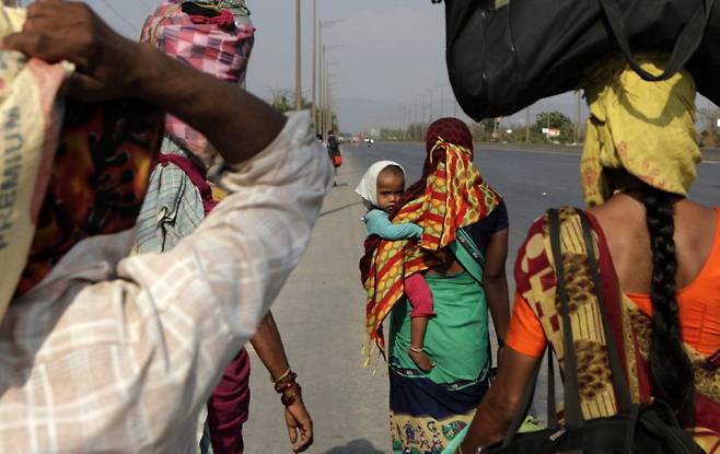 인도 이주 노동자들이 지난 3월29일 뭄바이 인근 고속도로에서 자녀를 안고 짐을 진 채 고향을 향해 걸어가고 있다. AP연합뉴스