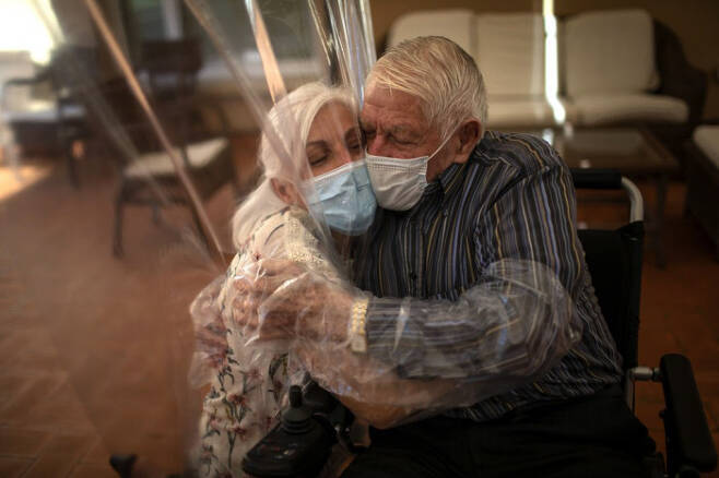 돌로레스 레예스 페르난데스(61)가 지난 6월22일 스페인 바르셀로나의 한 요양원에서 비닐 방역 커튼을 사이에 두고 아버지(87)와 포옹을 하고 있다. AP연합뉴스