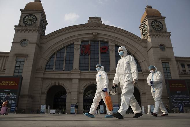 Workers in protective suits walk past the Hankou railway station in Wuhan in central China’s Hubei province on April 7, 2020. (AP-Yonhap)