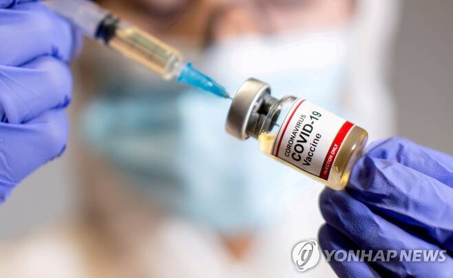 한 여성이 '신종 코로나바이러스 감염증(코로나19) 백신'이라고 쓰여있는 작은 병을 들고 있는 이미지. [로이터=연합뉴스 자료사진]