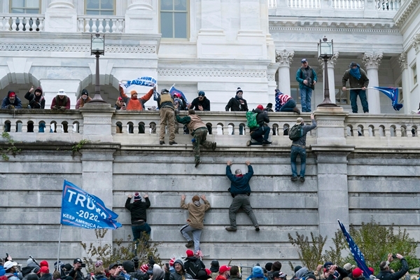 도널드 트럼프 미국 대통령 지지 시위대가 지난 6일(현지시간) 워싱턴DC 연방의회 의사당 서쪽 벽을 기어오르고 있다. AP 연합뉴스