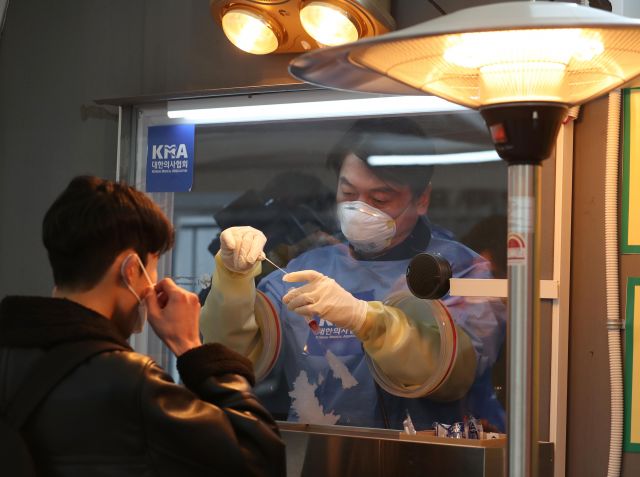 국민의당 안철수 대표가 15일 서울광장에 마련된 임시 선별검사소에서 의료 자원봉사에 나서 검채를 채취하고 있다. 연합뉴스
