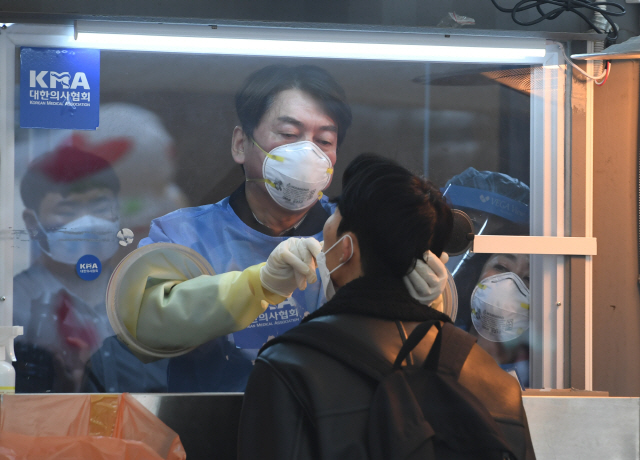 안철수 국민의당 대표가 15일 서울광장에 마련된 임시 선별검사소에서 의료 자원봉사에 나서 검체를 채취하고 있다. /연합뉴스