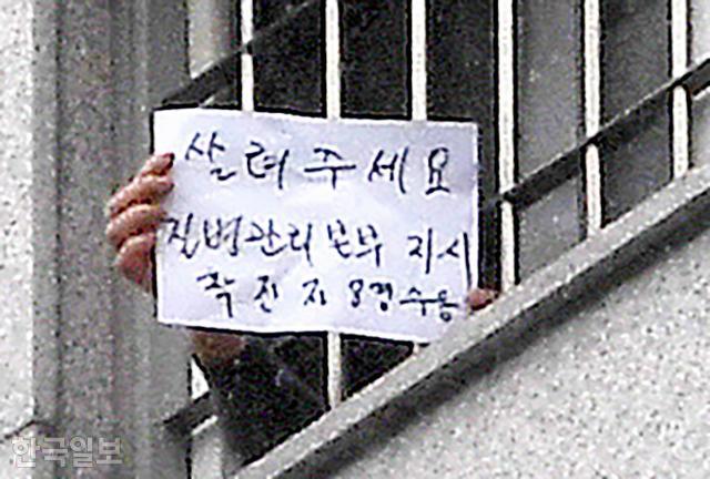 코로나19 집단 감염으로 확진자 750여명이 발생한 서울 송파구 동부구치소에서 지난달 29일 한 수용자가 '살려주세요. 질병관리본부 지시 확진자 8명 수용'이라고 쓴 종이를 밖으로 보이고 있다. 서재훈 기자