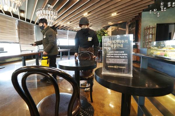 매장 이용 허가를 하루 앞둔 17일 오후 대구 달서구 이월드 내 카페에서 직원들이 방역작업과 더불어 치웠던 의자를 테이블마다 다시 놓고 있다. /연합뉴스