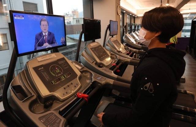 집합금지 시설이었던 헬스장의 조건부 영업이 허용된 18일 오전 서울 용산구의 한 헬스클럽에서 운동을 하는 시민이 문재인 대통령의 신년 기자회견을 시청하고 있다. 홍진환 기자 jean@donga.com
