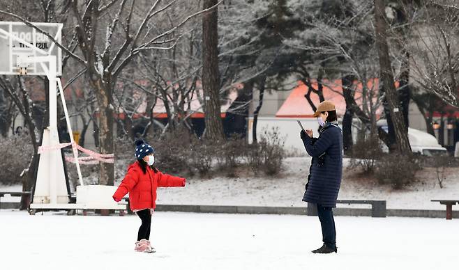 함박눈이 내린 18일 서울 여의도공원에서 한 모녀가 스마트폰에 추억을 남기고 있다.