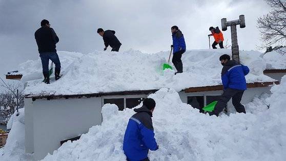 지난해 2월 경북 울릉군 공무원들이 주택 지붕에 쌓여있는 눈을 치우고 있다. 뉴스1