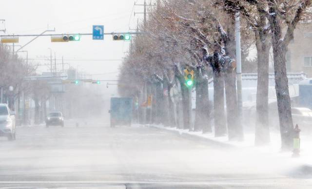 많은 눈이 내린 뒤 그친 18일 오후 강원 춘천시 사농동 일대 도로에 쌓인 눈이 바람에 날려 눈보라가 일고 있다./연합뉴스