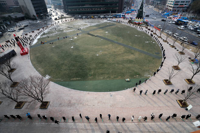 서울광장에 겨울이면 개장했던 야외 스케이트장(위 사진, 2014년 12월) 대신 2020년 12월17일 임시선별검사소가 설치되자 많은 시민들이 줄을 서서 순서를 기다리고 있다.