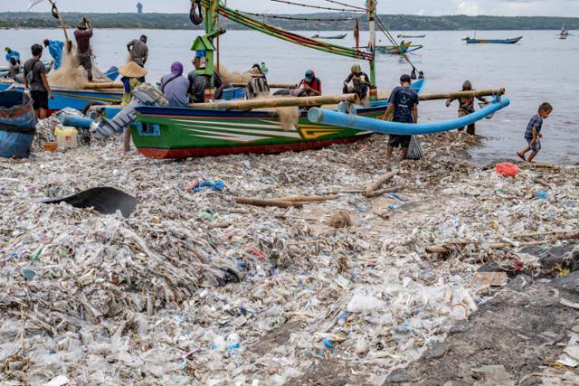 발리 끄동아난의 어촌에서 18일 어부들이 플라스틱 쓰레기가 덮인 해변에서 작업을 하고 있다. 발리=EPA 연합뉴스
