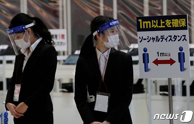 일본 도쿄의 한 전시회에서 사무국 직원들이 마스크와 얼굴 가리개를 착용한 채 업무를 보고 있다. © 로이터=뉴스1