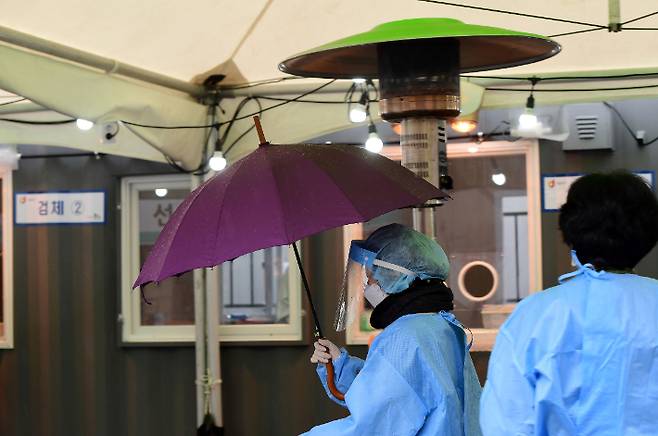 임시선별검사소에서 한 의료진이 우산을 쓰고 이동하고 있다. 황진환 기자