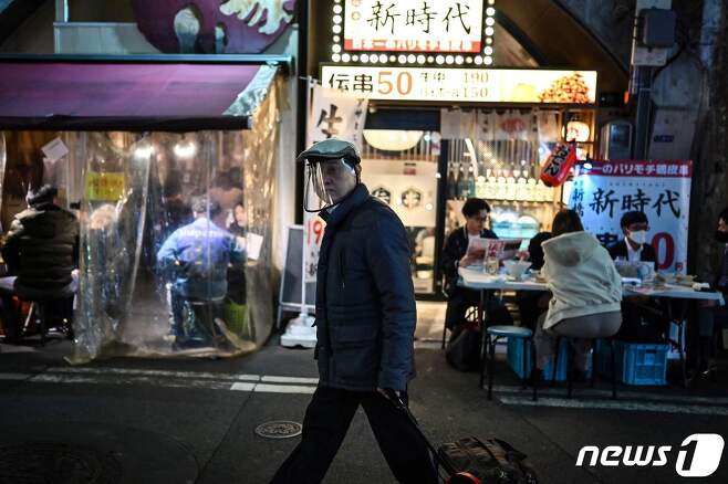 일본 도쿄 시내에서 한 남성이 투명 안면 가리개를 착용하고 길을 걷고 있다. © AFP=뉴스1