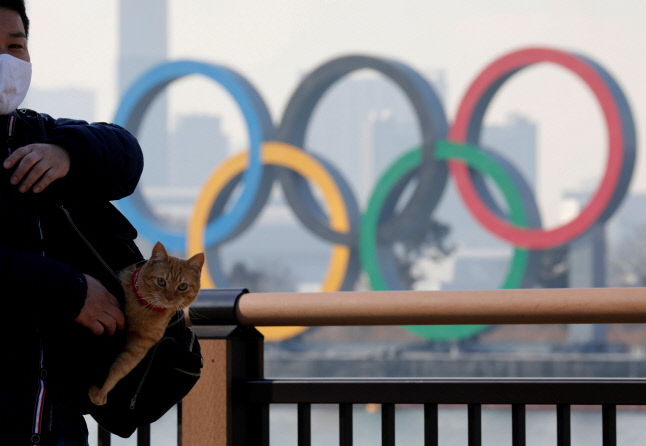 22일(현지시간) 한 남성이 마스크를 쓴 채 도쿄 올림픽 오륜기가 보이는 다리 옆을 지나가고 있다. 도쿄|로이터연합뉴스