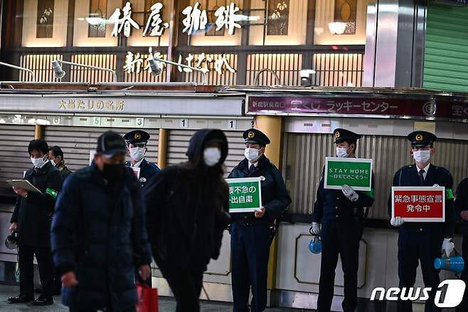 지난 22일 일본 도쿄시내에서 경찰들이 시민들에게 코로나19 '긴급사태 선언' 발령에 따른 불필요한 외출자제 등을 호소하고 있다. © AFP=뉴스1