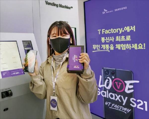 지난 22일 SK텔레콤이 개최한 갤럭시S21 사전 개통 행사에서 한 고객이 무인 매장에서 제품을 받은 뒤 기념촬영하고 있다. SK텔레콤 제공