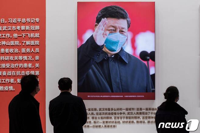 중국인들이 코로나19 방역 전시관에 걸린 시진핑 중국 국가주석의 사진을 관람하고 있다. © AFP=뉴스1
