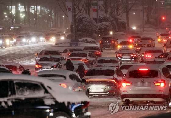 서울 전역에 대설주의보가 발효된 지난 6일 서울 삼성역 인근 도로에서 시민들이 차를 밀고 있다. 연합뉴스