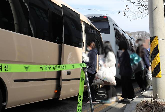 지난 25일 오후 대전시 중구 대흥동 IEM국제학교에서 신종 코로나바이러스 감염증(코로나19) 확진자들이 치료센터로 이동하기 위해 차량에 탑승하고 있다. 연합뉴스