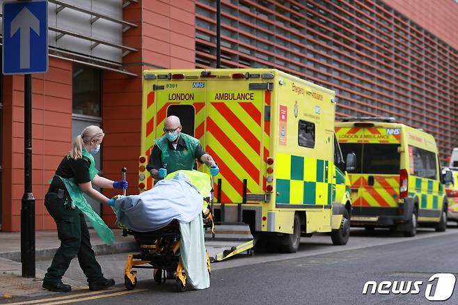 지난 26일(현지시간) 영국 런던 소재 왕립 런던 병원에서 의료진이 코로나19 환자를 이송 중이다. © 로이터=뉴스1
