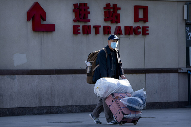 중국 최대 명절인 춘제(설) 특별운송 기간이 시작된 28일 수도 베이징의 기차역 앞에서한 남성이 짐 가방을 끌고 걷고 있다. 베이징/AP 연합뉴스