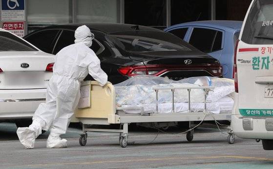지난해 신종 코로나바이러스 감염증(코로나19) 집단 감염이 발생한 서울 구로구 미소들요양병원에서 방호복을 입은 관계자들이 병실 거리두기를 위해 환자를 옆 건물로 이송하고 있다. 뉴스1