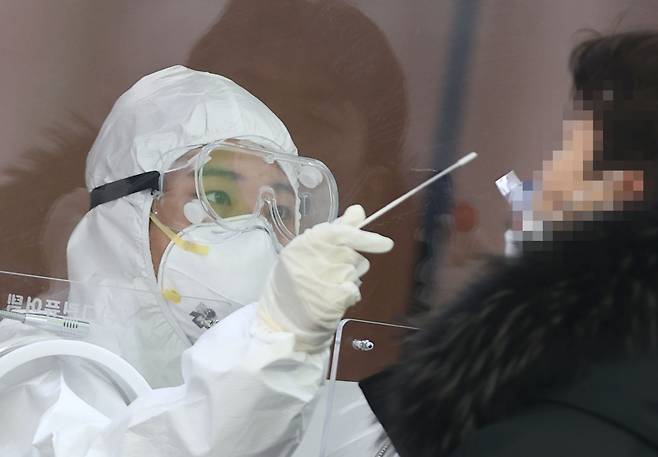 A medical worker collects a specimen with a long swab at a temporary coronavirus testing center in Seoul on Jan. 20. (Yonhap)