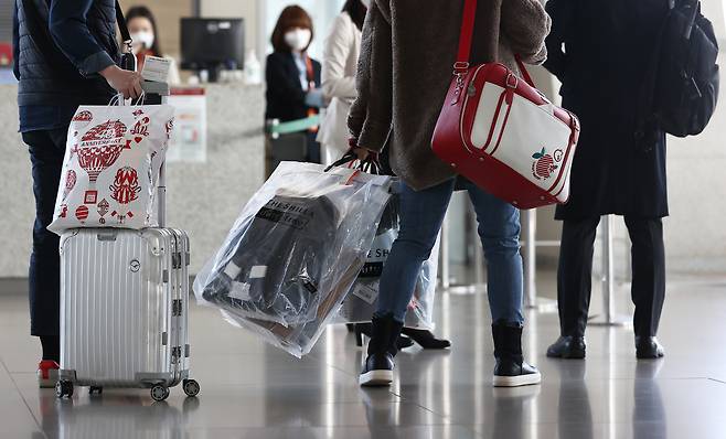 지난해 12월 12일 영종도 인천국제공항에서 제주항공 무착륙 관광비행을 떠나는 이용객들이 구입한 면세품을 들고 탑승구로 들어가고 있다. [연합]
