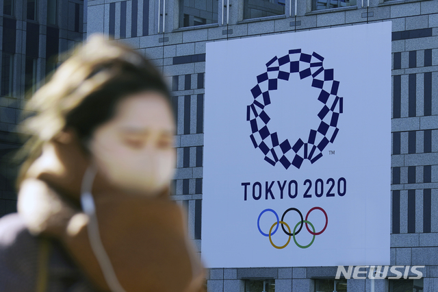 [도쿄=AP/뉴시스]지난달 19일 코로나19 예방을 위해 마스크를 쓴 한 여성이 일본 도쿄에서 2020 도쿄 올림픽 현수막 근처를 걷고 있다. 2021.01.19.