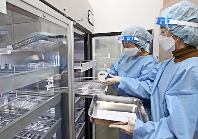 국내 첫 코로나19 백신 접종을 하루 앞둔 25일 오후 서울 동작구 보건소에서 백신접종 관계자가 아스트라제네카(AZ) 백신을 냉장고에 옮기고 있다. 동작구청 제공