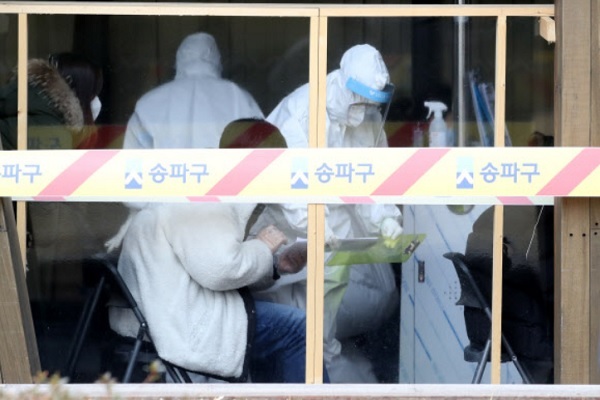25일 서울 송파구보건소 선별진료소에서 코로나19 검사를 받으려는 시민들이 문진표를 작성하고 있다. 뉴스1