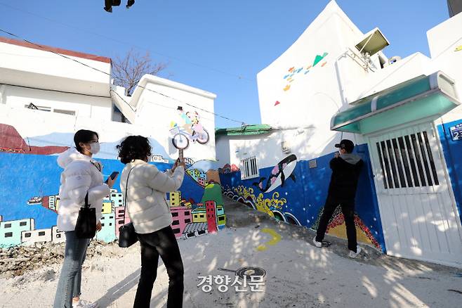 동피랑 벽화마을을 찾은 관광객들이 하얀 담장에 그려진 벽화를 배경으로 기념사진을 찍고 있다. 왼쪽 작품은 ‘통영항을 날다’, 오른쪽 작품은 ‘월척’이란 제목의 작품이다. 강구안과 통영 시내를 자전거를 타고 날아보면 어떤 느낌일까? 월척을 낚듯 내 꿈도 이루어지리라. 상상의 날개를 펴본다. /김영민 기자