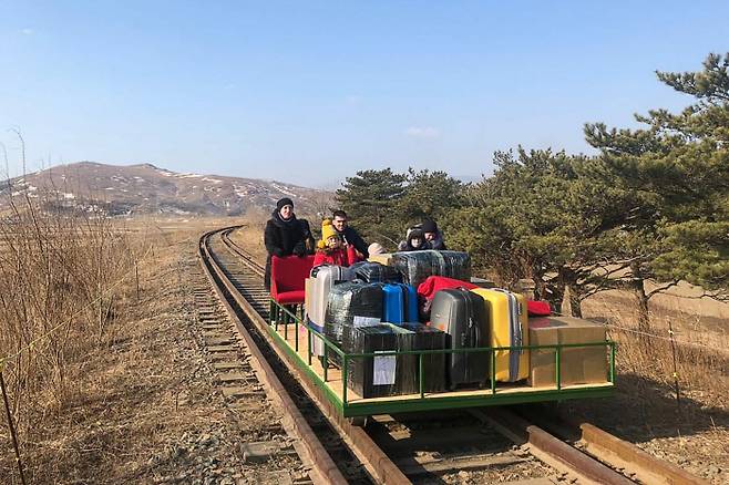 북한 주재 러시아 외교관들이 25일 짐이 든 수레를 직접 끌고 철로를 걸어 국경을 넘고 있다. 러시아외무부제공|타스통신연합뉴스