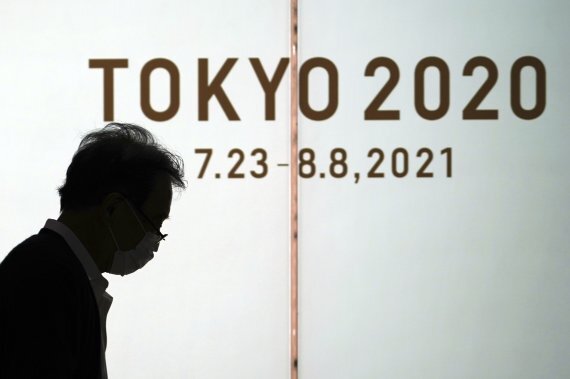 한 남성이 마스크를 쓴 채 도쿄올림픽 광고물 앞을 지나가고 있다. AP뉴시스