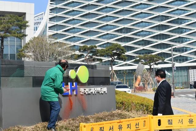 한 시민단체 대표가 8일 경남 진주 LH 본사에서 입간판 구조물에 고춧가루를 뿌리며 시위하고 있다. 뉴시스