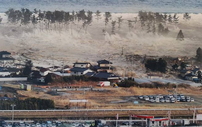 (도쿄 교도=연합뉴스) 규모 9.0의 동일본대지진이 발생한 직후인 2011년 3월 11일 오후 미야기(宮城)현 나토리시(市)의 한 마을이 밀려드는 쓰나미에 잠기고 있다. [자료사진]