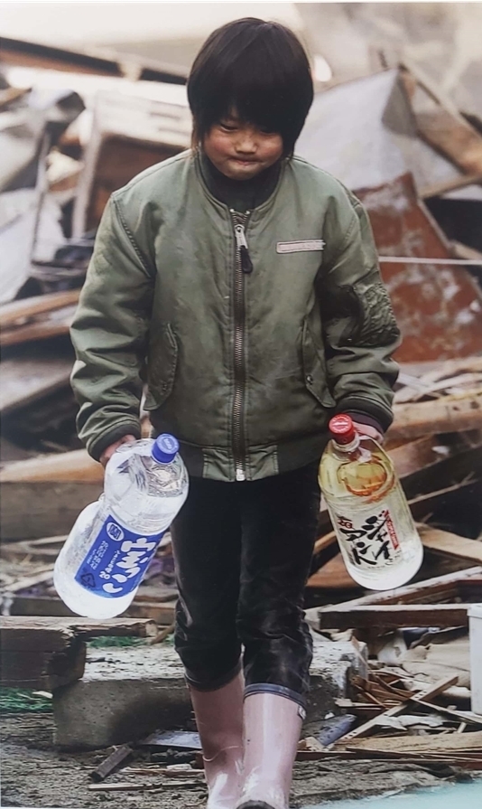 (도쿄 교도=연합뉴스) 동일본대지진 사흘 후인 2011년 3월 14일 폐허로 변한 미야기현 게센누마시(市)에서 마실 물이 든 페트병을 양손에 든 채 시무룩한 표정으로 걸어가는 소년. [자료사진]
