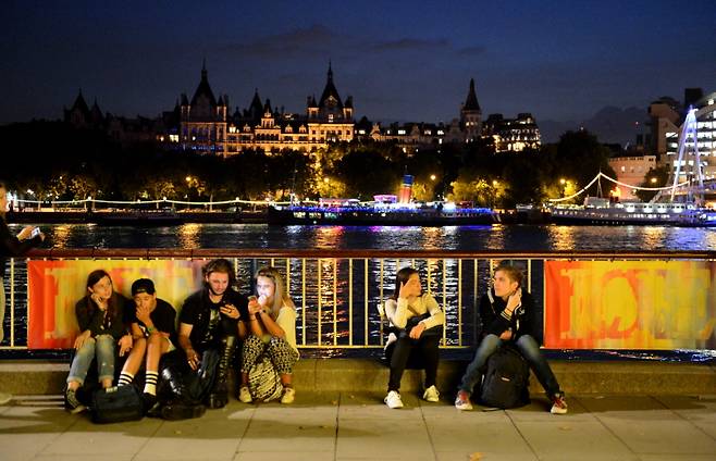 마스크를 쓰지 않은 젊은이들이 템스 강변에 앉아 있다
