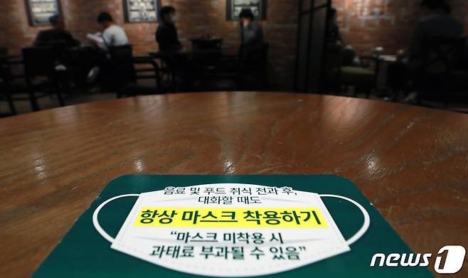 '마스크 착용 의무화 조치' 시행 첫날인 12일 오후 서울 시내의 한 커피전문점에 마스크 착용 안내 문구가 붙어 있다. 2021.4.12/뉴스1 © News1 구윤성 기자