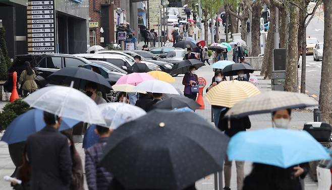 정부가 '사회적 거리 두기' 조치를 3주간 연장한 가운데 12일 오후 서울 서초구 서초대로 인근에서 직장인들이 우산을 쓴 채 걸어가고 있다./연합뉴스